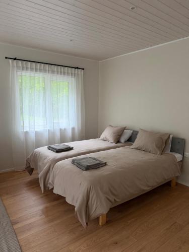 a white bedroom with two beds and a window at Nurmeveski Holiday House in Nurme