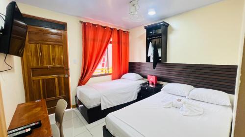 a hotel room with two beds and a window at Hotel Costa del Sol in Puerto Limón