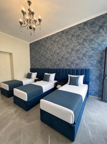 a room with three beds and a chandelier at Yolyans Hotel in Goris