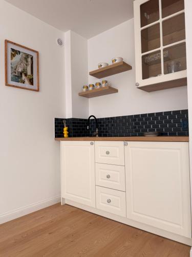 a kitchen with white cabinets and a black counter top at White Villa in Darlowko