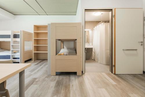 a room with a bunk bed and a room with a desk at Ostello Sport Center in Monte Ceneri