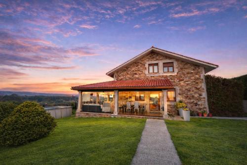 a stone house with a sunset in the background at Casa abuelo Ramón in Narón