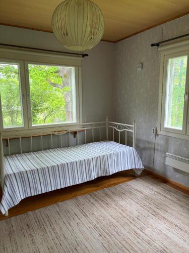 a bed in a room with two windows at Tamminiemi in Luodonmaa
