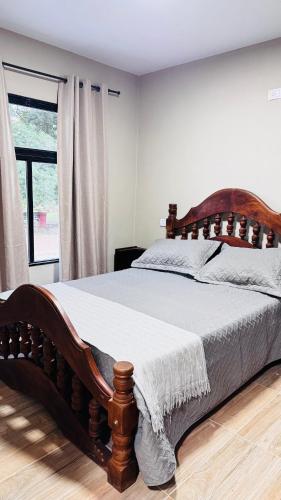 a large wooden bed in a bedroom with a window at SomosRio II Apart in La Cruz