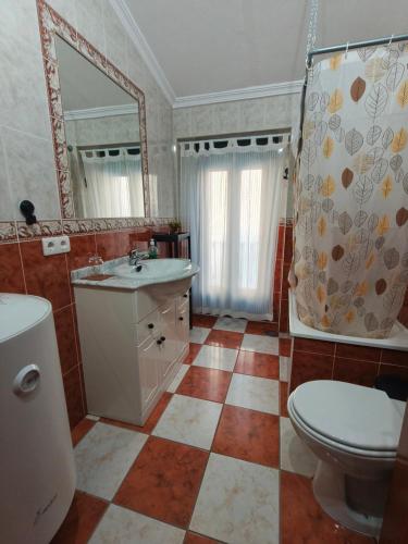 a bathroom with a sink and a toilet and a mirror at El Refugio in Aracena
