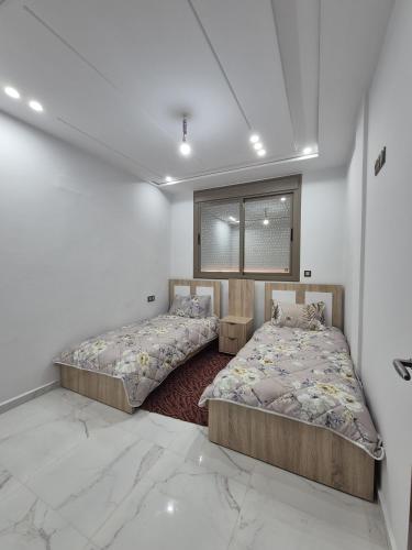 two beds in a room with white walls at Calm and facinating vacation in Saïdia