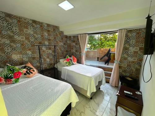 a room with two beds and a window with a view at Pousada e Restaurante Morena Raiz in Olinda