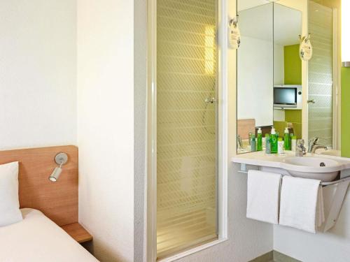 a bathroom with a sink and a shower with a mirror at ibis budget Wrocław Stadion in Wrocław