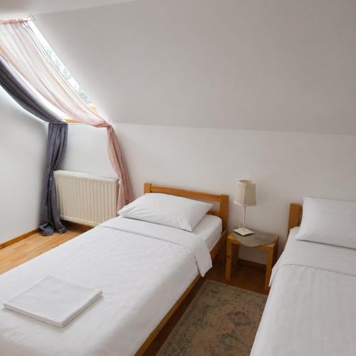 two twin beds in a room with a window at Apartman Čardak in Gospić