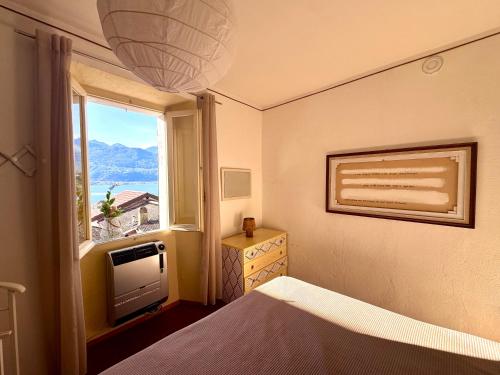 a bedroom with a bed and a television and a window at Piccolo Borgo vista lago di Como by Gottschalk in Dorio