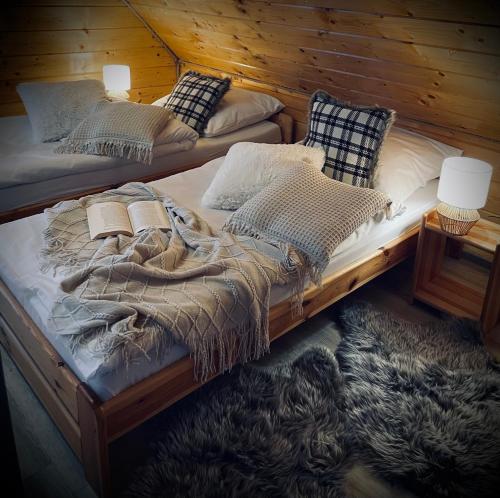 two twin beds in a room with a wooden wall at Domki Zielony Raj Rabka- Zdrój Jacuzii na wyłączność Sauna in Rabka-Zdrój