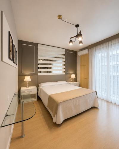 a bedroom with a large bed with two tables and two lamps at Curitiba Palace Hotel in Curitiba