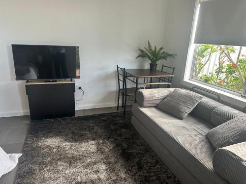 a living room with a couch and a flat screen tv at The Hunter Studio in Cessnock