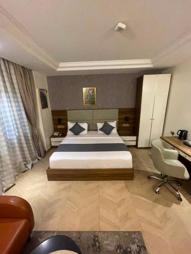 a bedroom with a bed and a desk and a chair at CARITAS HOTEL AND suite in Araromi