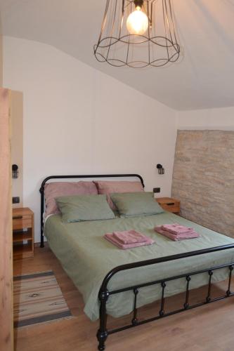 a bedroom with a bed with green sheets and a chandelier at Casa Evelina in Čepić