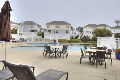 a patio with tables and chairs next to a pool at 36967 S. Silver Sands Dr, Bethany Beach in Bethany Beach
