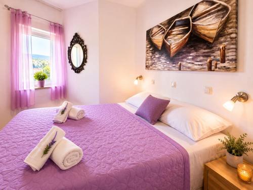 a bedroom with a purple bed with towels on it at Adriatic Star in Banjol