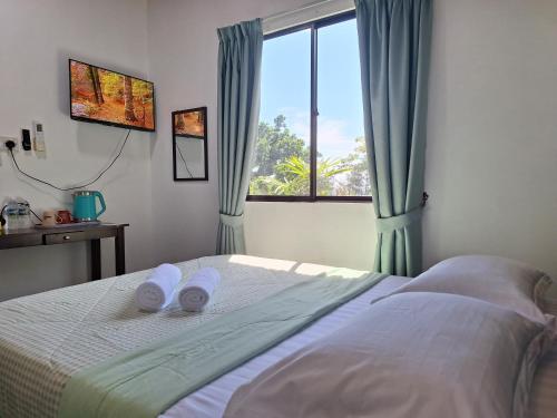 a bedroom with a bed with slippers on it at Mutodon Green in Kuala Penyu