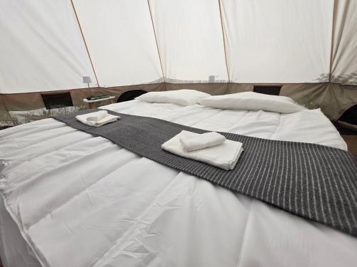 a bed in a tent with two towels on it at Acorn Creek Tented Camp in Nidda