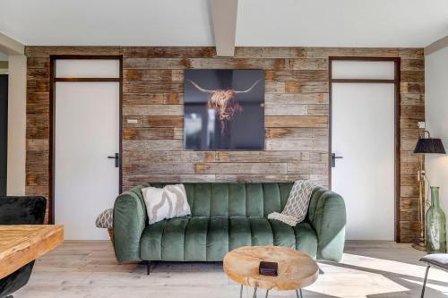 a living room with a green couch at Vrijstaande bungalow met grote privé tuin dichtbij Veerse meer in Kortgene