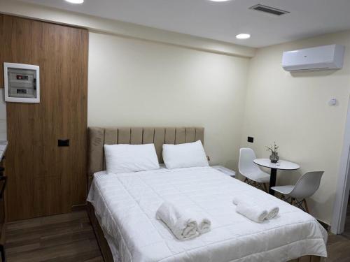 a bedroom with a large white bed with towels on it at EDEAN Apartments 4 in Tirana