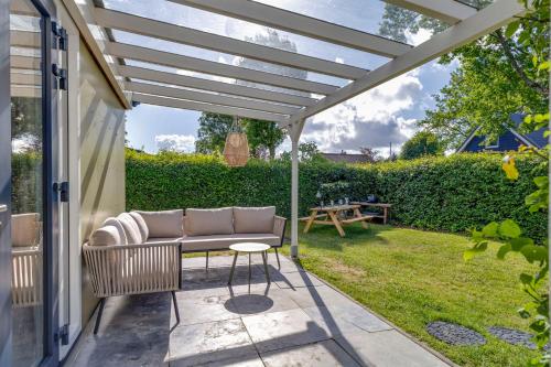 a patio with a couch under a pergola at Vrijstaande bungalow met grote privé tuin dichtbij Veerse meer in Kortgene