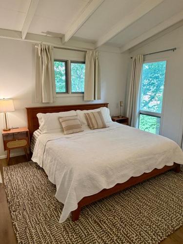 a large white bed in a bedroom with windows at Manville Heights Modern in Iowa City