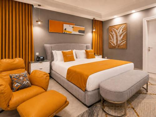 a bedroom with a large bed and a chair at The Alima Suites in Accra