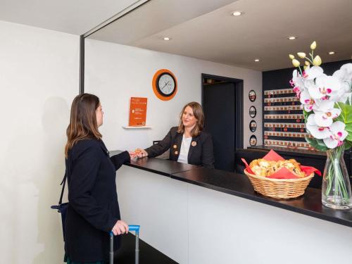 two women shaking hands at a counter in a store at Aparthotel Adagio Access La Défense - Place Charras in Courbevoie