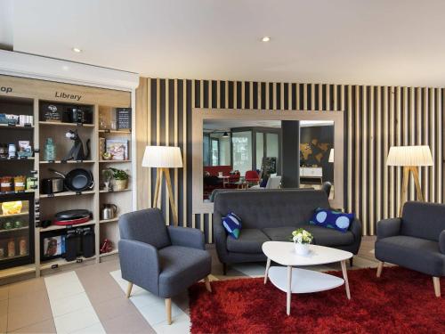 a living room with two chairs and a couch and a table at Aparthotel Adagio Access Strasbourg Illkirch in Illkirch-Graffenstaden