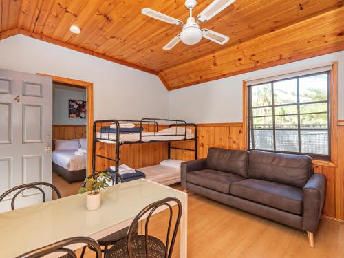 a living room with a couch and bunk beds at Wairo Beach Holiday Park in Lake Tabourie