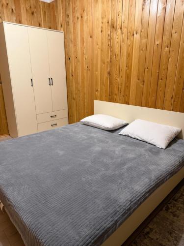 a bedroom with a bed and wooden walls at Kausar cottage in Cholpon-Ata