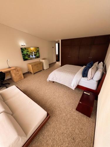 a large bedroom with two beds and a television at D'Acosta Hotel Belencito in Nobsa