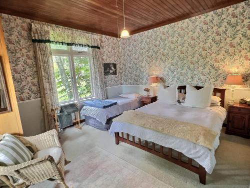 a bedroom with two beds and floral wallpaper at The Rabbiter's Cottage in Kahuranaki