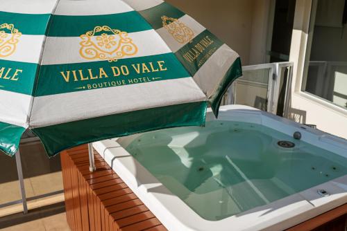 a jacuzzi tub with an umbrella on a balcony at Villa do Vale Boutique Hotel in Blumenau