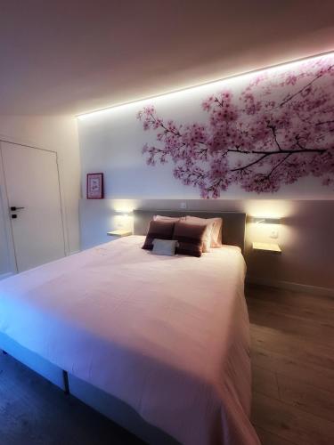 a bedroom with a large bed with a flower painting on the wall at Zaza Suites in Middelkerke