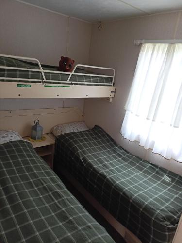 two beds in a small room with two windows at Chatka in Nasutów
