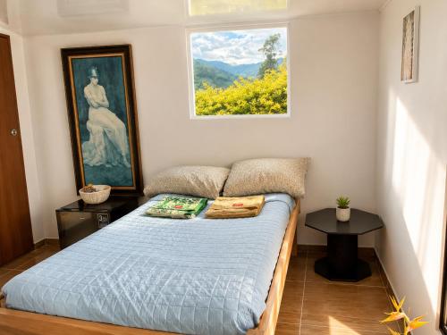 a bedroom with a bed and a painting on the wall at ECOHostal Las Hamacas Rincon Del Árbol in Villamaría