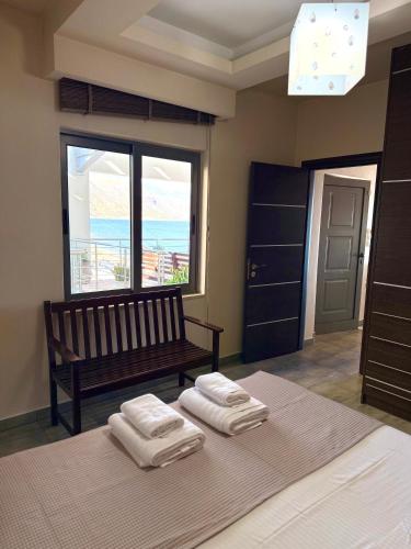 a bedroom with a bed and a bench and a window at Gonis Suites in Palaiochora