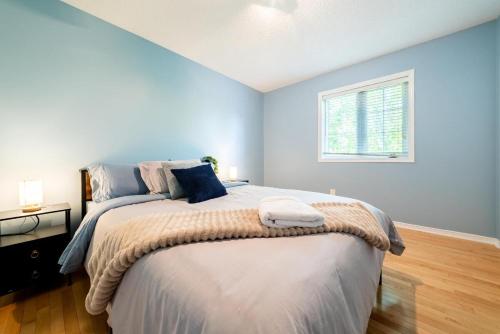 a bedroom with a large bed with blue walls and a window at Pool, BBQ & Foosball Spacious 4BR Home in Gatineau