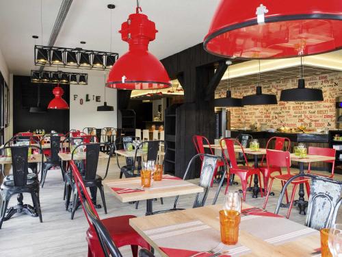 a restaurant with tables and chairs and red chandeliers at ibis Styles Chartres Métropole in Chartres