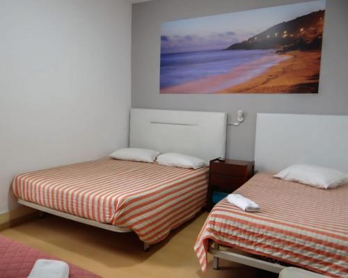 two beds in a room with a picture of the beach at Residencial Moderna in Figueira da Foz