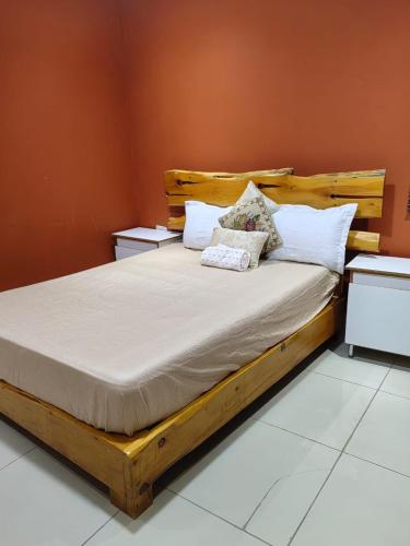 a wooden bed with pillows on it in a room at Qten Camp in Pietermaritzburg