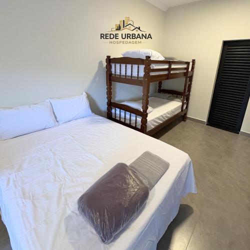 a bedroom with a white bed with a brown blanket on it at Loft 9 com ar-condicionado da Rede Urbana in Indaiatuba