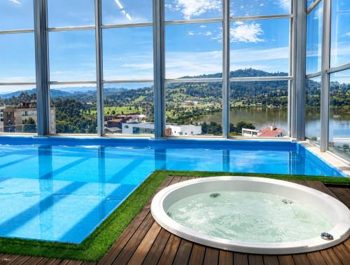 a large swimming pool with a tub in a room with windows at APARTAMENTO FAMILIAR EN PAIPA RÚSTlCO 70-9 in Paipa