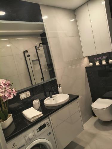 a bathroom with a sink and a washing machine at Mazury Glam Studio in Giżycko
