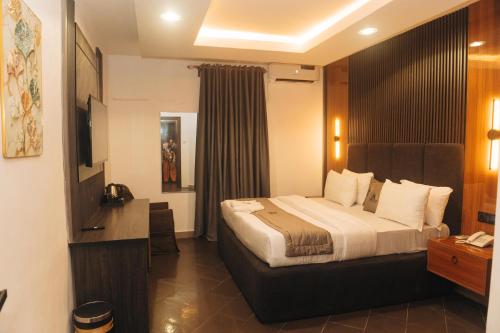 a hotel room with a bed and a television at Muster Point Hotel & Suites in Port Harcourt