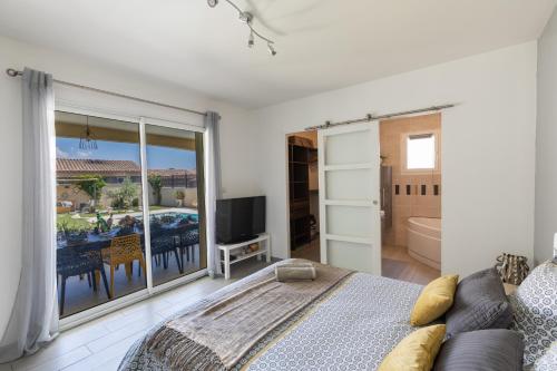 a bedroom with a bed and a tv and a balcony at Olympe de Provence in Caromb