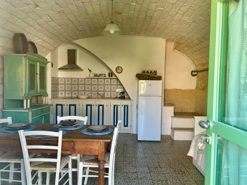 a kitchen with a table with chairs and a refrigerator at Pedra e Lozzu in Sedini