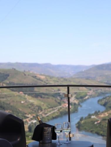 two wine glasses on a table with a view of a river at Casa Vale do Douro in Mesão Frio